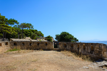 Fortezza fortress wall with loopholes. green Mediterranean pines and cedars