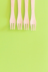 Fork setup Cutlery pattern on a bright green background. Eco-friendly wooden disposable cutlery on bright backdrop. Wallpapers for modern and ecological food. Plastic Free background for food banner
