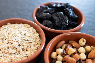 Healty, vegetarian dried fruit breakfast. Set of bowls with dried fruit to enrich a healthy vegan breakfast. Oats, almonds and plums to be included as a snack for a diet for beauty and health behavior