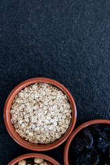 Healty, vegetarian dried fruit breakfast. Set of bowls with dried fruit to enrich a healthy vegan breakfast. Oats, almonds and plums to be included as a snack for a diet for beauty and health behavior
