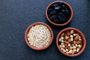 Healty, vegetarian dried fruit breakfast. Set of bowls with dried fruit to enrich a healthy vegan breakfast. Oats, almonds and plums to be included as a snack for a diet for beauty and health behavior