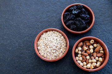 Healty, vegetarian dried fruit breakfast. Set of bowls with dried fruit to enrich a healthy vegan breakfast. Oats, almonds and plums to be included as a snack for a diet for beauty and health behavior