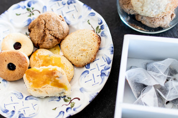 Homemade sweet cookies for afternoon snack, traditional home-made artisan pastry. decorated plate of biscuits on a black stone. Snack and tea time with biscuits. grandmother's sweets tasting set-up