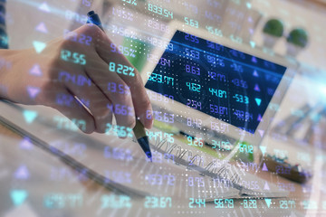 Financial forex graph drawn over hands taking notes background. Concept of research. Double exposure