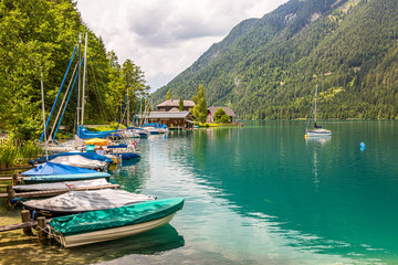 Sailing and paddle boats on boat pier at east shore of Weissensee in Austria in autumn