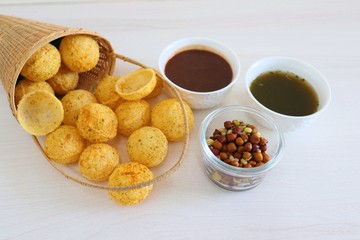 Panipuri or Golgappa. Indian street snack made of fried mint flavors puries, mint chutney, sprouts and dates, tamarind chutney. Indian Chat.