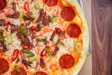 Pizza with Mozzarella cheese, salami, Tomatoes, hot pepper, Spices. Italian pizza on wooden table background