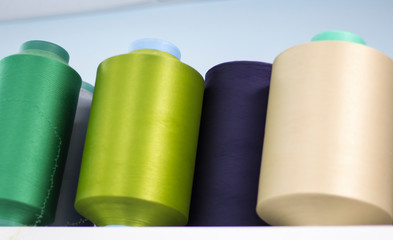 colored elastic threads wound on bobbins are on the shelf in the production view from below