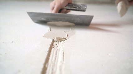 Worker aligns the wall with construction putty. a close shot at the builder hands, who level the...
