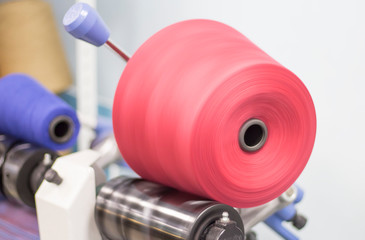 on a yarn rewinding machine, in production, the pink thread is rewound into a bobbin