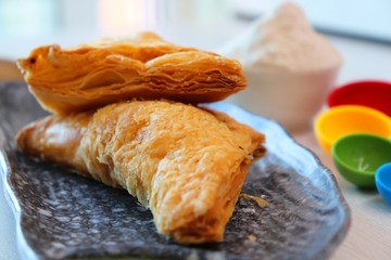 Puff pastry triangles filled with Vegetables like carrots, potatoes, peas and beans with some spices on wooden table