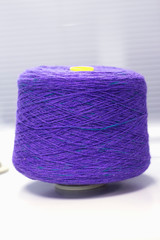 bobbin with purple yarn on a knitting machine