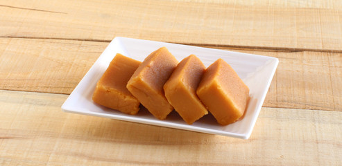 Mysore pak, a traditional, popular, and delicious sweet dish native to the city of Mysore, Karnataka, India, is made from ingredients like gram flour, ghee and sugar, on a ceramic plate.