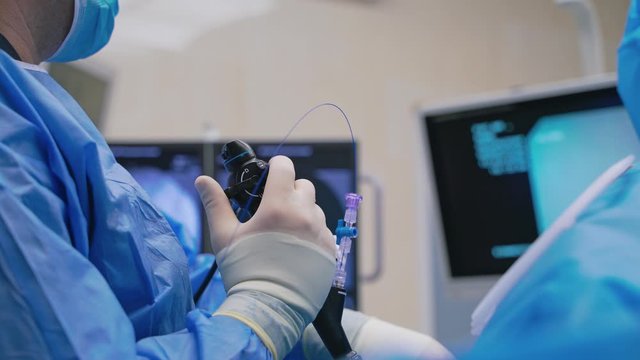 New technologies in surgery. Close-up doctor's hand with modern equipment during the operating process on monitors background. Medical concept.