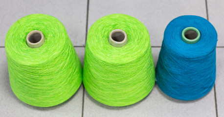 three colored threads wound on bobbins in production top view