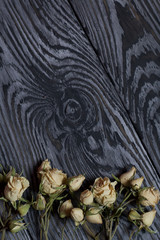 A bouquet of dried roses. Against the background of aged wooden boards with a black structure.