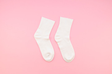 Flat lay Pair of white cotton socks on a pastel pink background. Top view children's socks