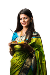 Indian young female in saree holding Pooja Thali standing isolated against white background,...