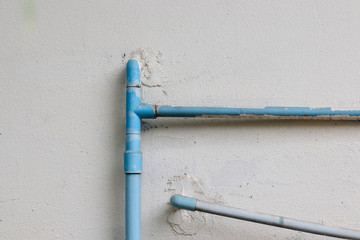 PVC water pipe on white concrete wall background outside of the house