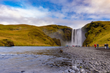 Skogafoss waterfall seen from afar with unrecognisable visitors, Iceland