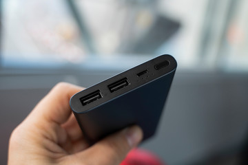 Man is holding the power bank a an the charger. Powerbank in hand. Power-saving device for smartphone and other devices. Helping to charge your phone.