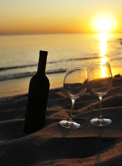 Wine glasses with red wine on sand on the beach. Valentine's Day concept.