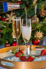 Champagne poured into glasses with strawberries on festive background