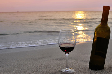Wine glasses with red wine on sand on the beach. Valentine's Day concept.