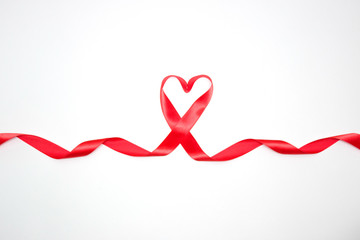 Beautiful red satin ribbon isolated on white background in the form of heart and developing ends. Design for holidays, Valentine's day