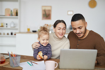 Portrait of smiling mixed race family using laptop together while shopping online, copy space