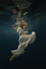 Girl in a beautiful dress swims underwater