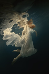 Girl in a beautiful dress swims underwater
