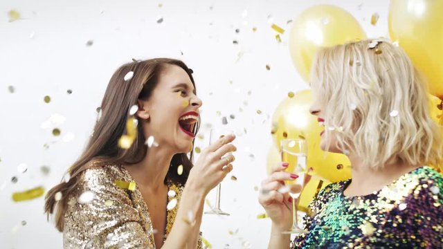 Woman drinking champagne and dancing among confetti