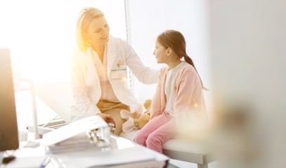 Naklejka premium Smiling doctor talking to girl patient at hospital