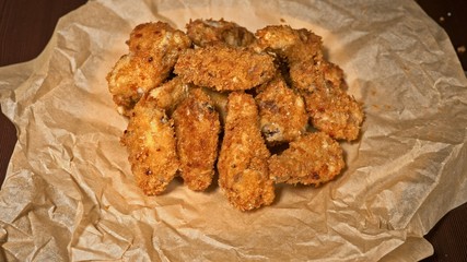 Cool beautiful fresh juicy cooked chicken wings in breading. Buffalo wings spread on food white plate in table. Very tasty and beautiful. Cooking with deep fryer fry machine.