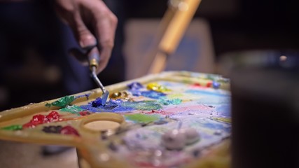 Obraz premium Artist copyist paint seascape with ship in ocean. Craftsman decorator draw as boat sail on blue sea with acrylic oil color. Draw finger, brush, knife palette. Indoor. Close up cinematic look.