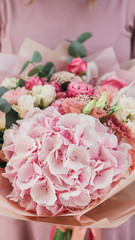 Colorful bouquet of different fresh flowers in the hands of a florist woman. Rustic flower background. Craft bouquet of flowers.