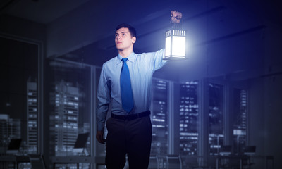 Scared businessman holding glowing lantern © adam121