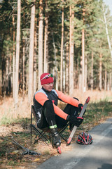 Training an athlete on the roller skaters. Biathlon ride on the roller skis with ski poles, in the helmet. Autumn workout. Roller sport. Adult man riding on skates. Athlete is getting ready to start.