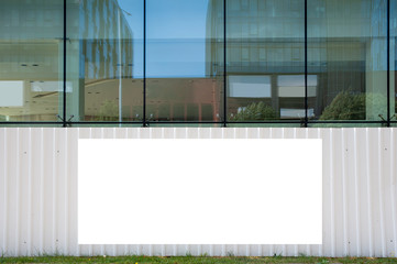 Blank white banner for advertisement mounted on the fence of construction site on a sunny day.