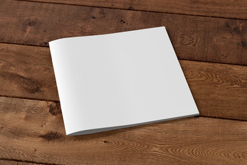 Square brochure or booklet cover mock up on wooden background. Isolated with clipping path around brochure. Side view. 3d illustratuion