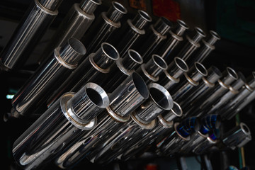 New and used motorcycle exhaust chrome pipes in a motorcykles shop or in service center.