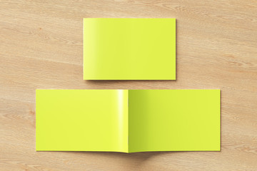 Yellow horizontal brochure or booklet cover mock up on wooden background. Closed one brochure and upside down other. Clipping path around brochure. View above. 3d illustratuion