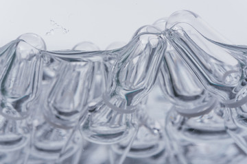 Glass medical ampoule vial for injection. Medicine is liquid sodium chloride with of aqueous solution in ampulla. Close up. Bottles ampule multicolor on background color and water. Human plasma.