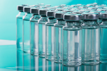 Glass medical ampoule vial for injection. Medicine is liquid sodium chloride with of aqueous solution in ampulla. Close up. Bottles ampule multicolor on background color and water. Human plasma.