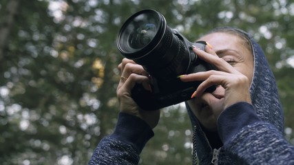 Traveler photographing scenic view in forest. One caucasian woman shooting close up look. Girl take photo video on dslr mirrorless camera. Professional photographer travel with backpack. Outdoor.