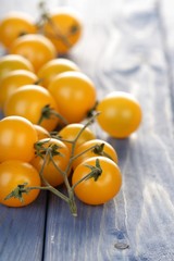 Bunch of yellow cherry tomatoes on wooden table