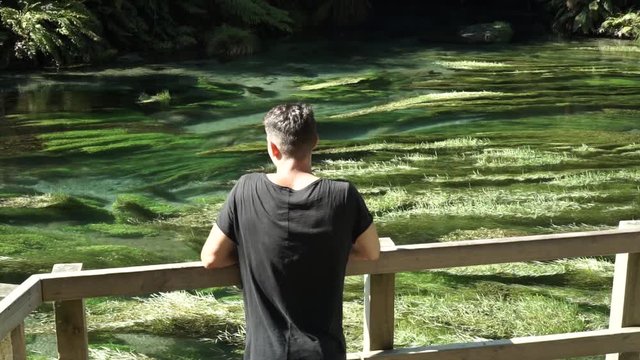 SLOWMO - Caucasian man standing by Putaruru Blue Spring, New Zealand