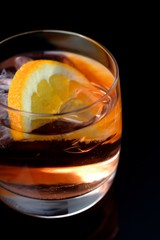 Glass of whiskey and ice on black background