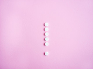 Weiße Tabletten als Ausrufezeichen auf einem rosa Hintergrund, Nebenwirkung